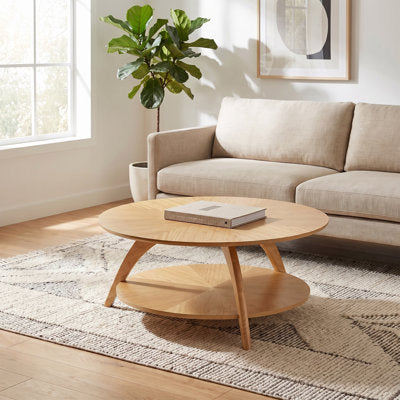 Round coffee table with tapered three-leg base and lower shelf
